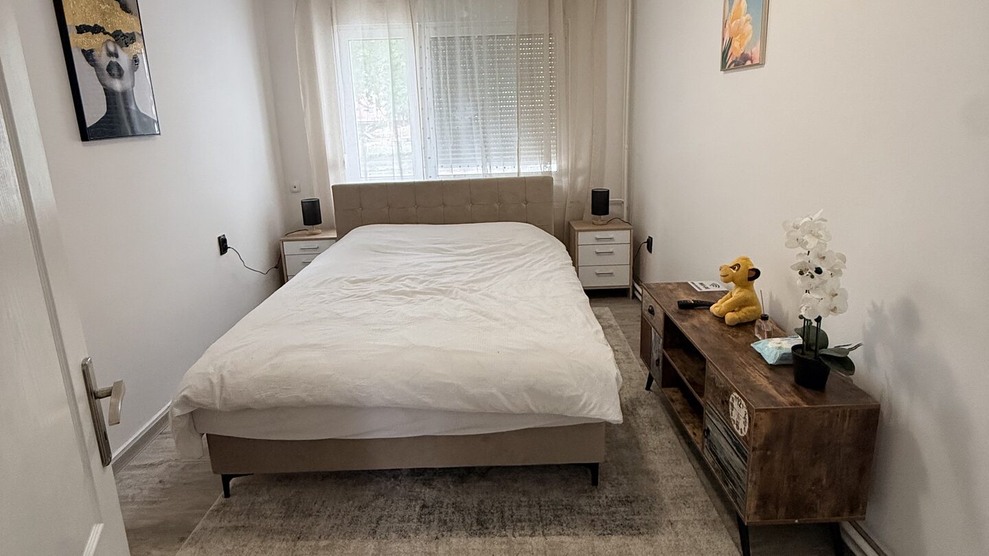 Bright bedroom of Apartment Lola in Doboj with a queen bed, rustic wooden TV console and soft grey rug